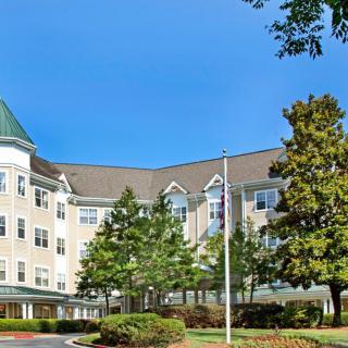 A multi-story building surrounded by trees under a clear blue sky.