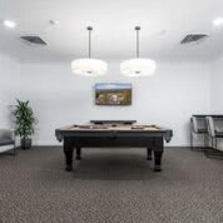 A modern game room featuring a pool table with stylish lighting.