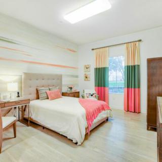 A modern and stylish bedroom featuring a comfortable bed, elegant desk, and colorful curtains.