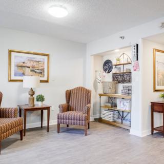A cozy lobby area featuring striped armchairs, artwork on the walls, and a small table with decorative items.