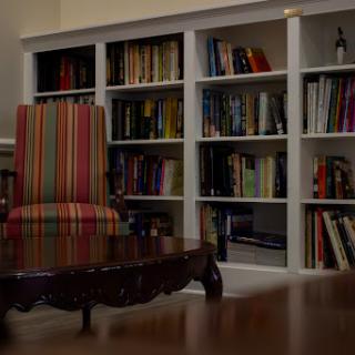 A cozy reading corner featuring a striped chair and shelves filled with books.