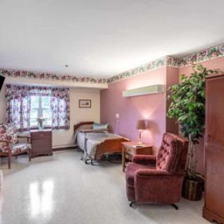 A hospital room furnished with a bed, chairs, and decorative elements.