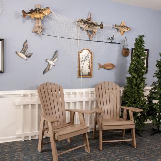 A cozy corner featuring wooden chairs surrounded by nautical-themed decor, including submarine and seagull wall art, with indoor plants adding a touch of greenery.