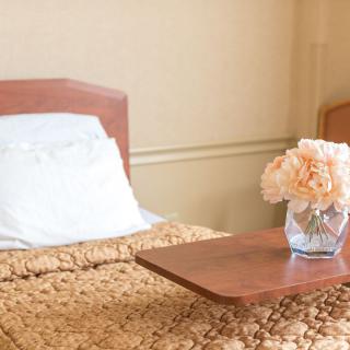 A cozy bedroom with a neatly made bed and a vase of flowers on the side table.
