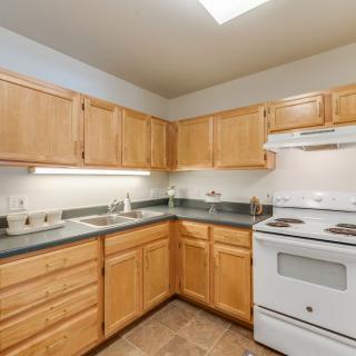 A kitchen with wooden cabinets, a white stove, and sink.