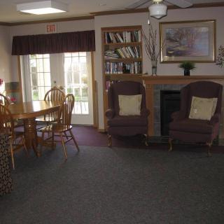 A cozy living room featuring a dining table, bookshelf, and fireplace.