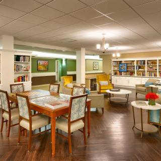 A cozy lounge area with bookshelves, comfortable seating, and a table and chairs.