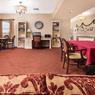 A cozy living and dining area with red carpeting, featuring comfortable furniture and homely decorations.