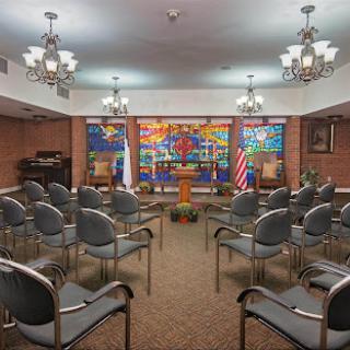 A room set up with chairs for an event, featuring colorful artwork and national flags.