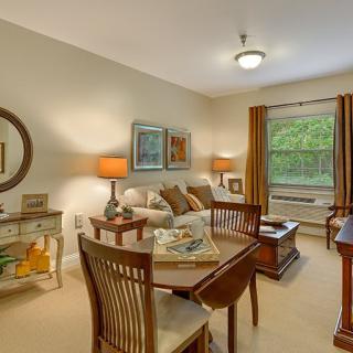 A cozy living room with a dining area, decorated with warm tones and elegant furniture.