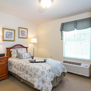 A cozy bedroom with a single bed, bedside lamp, and framed artwork on the walls.