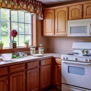A cozy kitchen with wooden cabinets, a stove, and a window view.