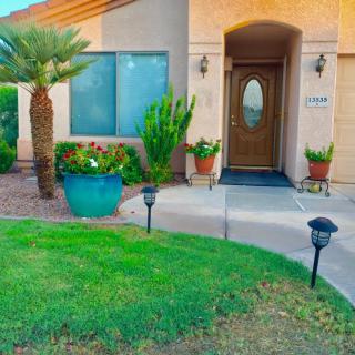 A beautifully landscaped front yard with potted plants lining the pathway to a welcoming house entrance.
