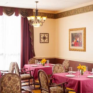 A cozy dining room with tables set for a meal, adorned with decorative elements like a chandelier and framed art.