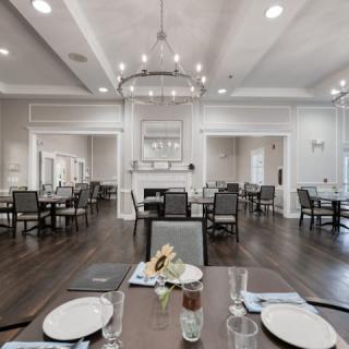 A spacious and elegantly decorated dining room with neatly arranged tables and chairs under a large chandelier.