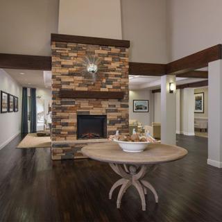 A cozy living room interior featuring a central stone fireplace, hardwood flooring, and a stylish wooden table.