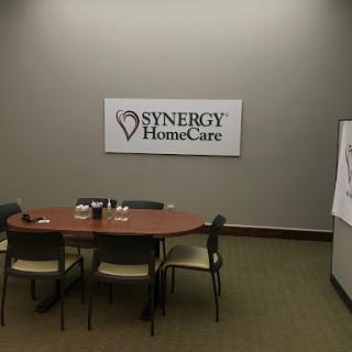 A meeting room setup featuring Synergy HomeCare branding.
