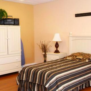 A cozy bedroom with a striped bedspread, white furniture, and a decorative lamp.