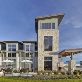 A modern building with a stone facade and outdoor seating area under a clear blue sky.