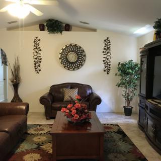 A cozy living room with leather sofas, a coffee table adorned with flowers, and decorative wall art.