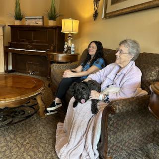 A young woman and a senior woman enjoying a cozy moment together in a living room with a dog.