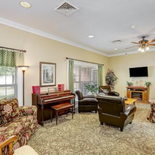 A cozy living room featuring a piano, comfortable seating, and a television.