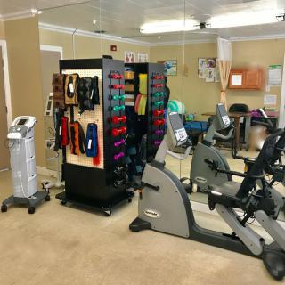 A small gym with various exercise equipment, including stationary bikes and weights.