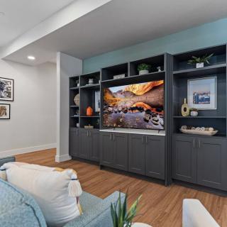 A modern living room featuring an entertainment center with a large television and built-in shelving, offering a comfortable and stylish space.