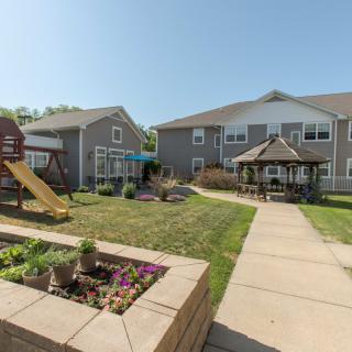 Apartment complex courtyard featuring a playground, gazebo, and garden.