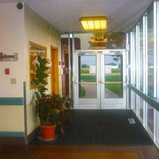 A hallway with potted plants leading to a set of glass doors.