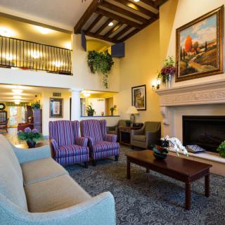 A cozy living room with comfortable seating, artwork on the walls, and a warm fireplace.