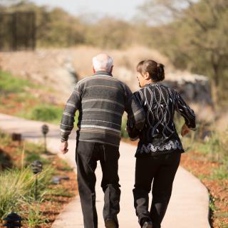 An elderly couple walking together along a scenic pathway.