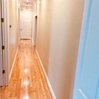 A long, narrow hallway with polished wooden floors and several doors along the sides.