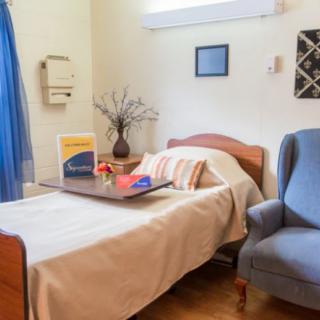 A tidy and well-decorated hospital room with a single bed and comfortable chair.