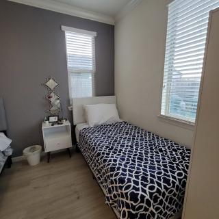 A modern, minimalist bedroom featuring a single bed with patterned bedding and a small nightstand.