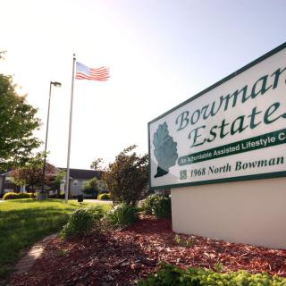 An outdoor view of the Bowman Estates sign with an American flag in the background.
