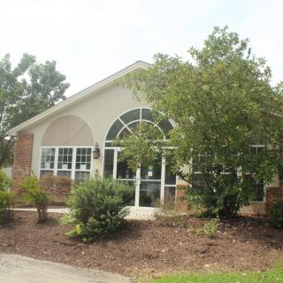 A well-landscaped residential house with large windows and brick exterior.