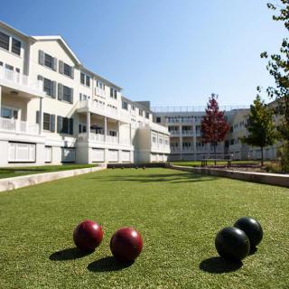 A lawn with bocce balls in front of a residential building complex on a sunny day.