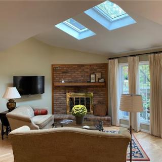 A cozy living room featuring a brick fireplace, skylights, and comfortable seating.