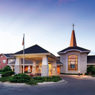 A striking church building featuring modern architecture and a welcoming entrance, illuminated by the evening light.