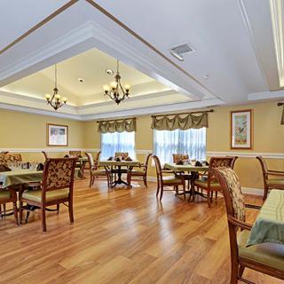 An elegantly designed dining room with multiple tables and chairs, featuring warm lighting and a wooden floor.