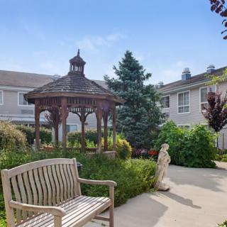 A serene garden with a wooden gazebo, surrounded by lush greenery and pathways.