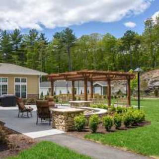 A beautifully landscaped garden with a pergola and seating area, surrounded by lush greenery.