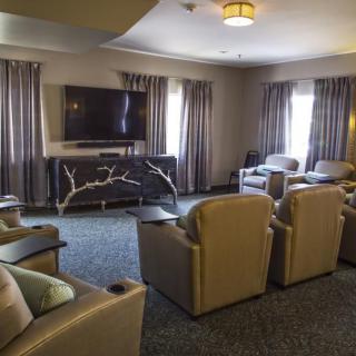 A cozy living room setup with multiple chairs facing a television, surrounded by elegant curtains.