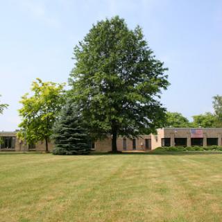 A serene view of a building surrounded by lush greenery and a well-maintained lawn.