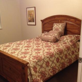 A cozy bedroom with a wooden bed and floral patterned quilt.