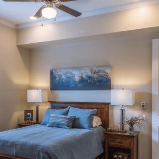 A cozy bedroom with blue bedding, nightstands, and soft lighting.