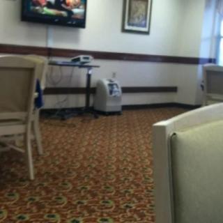 A waiting room with chairs, a television, and patterned carpet.