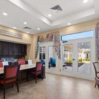A well-lit meeting room with a large table and chairs, overlooking a patio through glass doors.