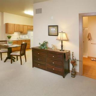 A cozy apartment interior featuring a dining area and kitchen with wooden cabinets and furniture.